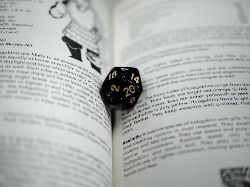 The 14 Must-Have Tools for Dungeon Masters 3 dice inside a DND rule book